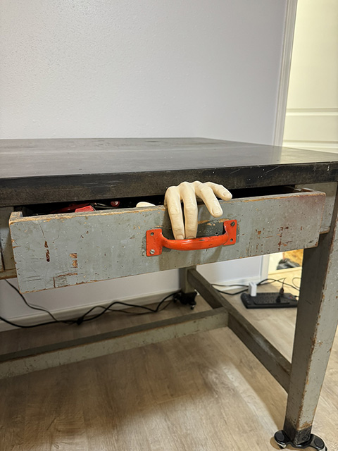 The third handle and the hand together. The photo lands at the structural threshold — the speaker has just finished describing the second drawer's bleeding and is about to begin the third drawer's slow approach.