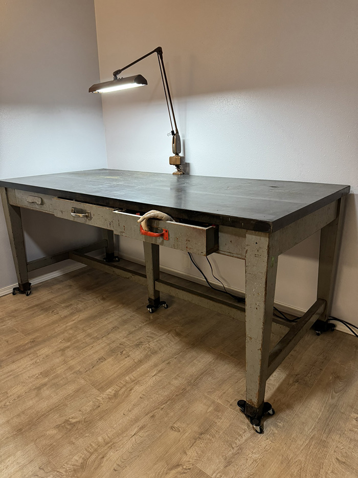 The pull-back. The reader's perspective widens to the full bench again. The drawer is still open; the hand is still there; the speaker has retreated but the bench remains unmoved.