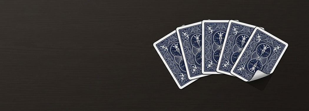 Overhead illustration of five playing cards fanned face down on a dark table with one corner lifting.